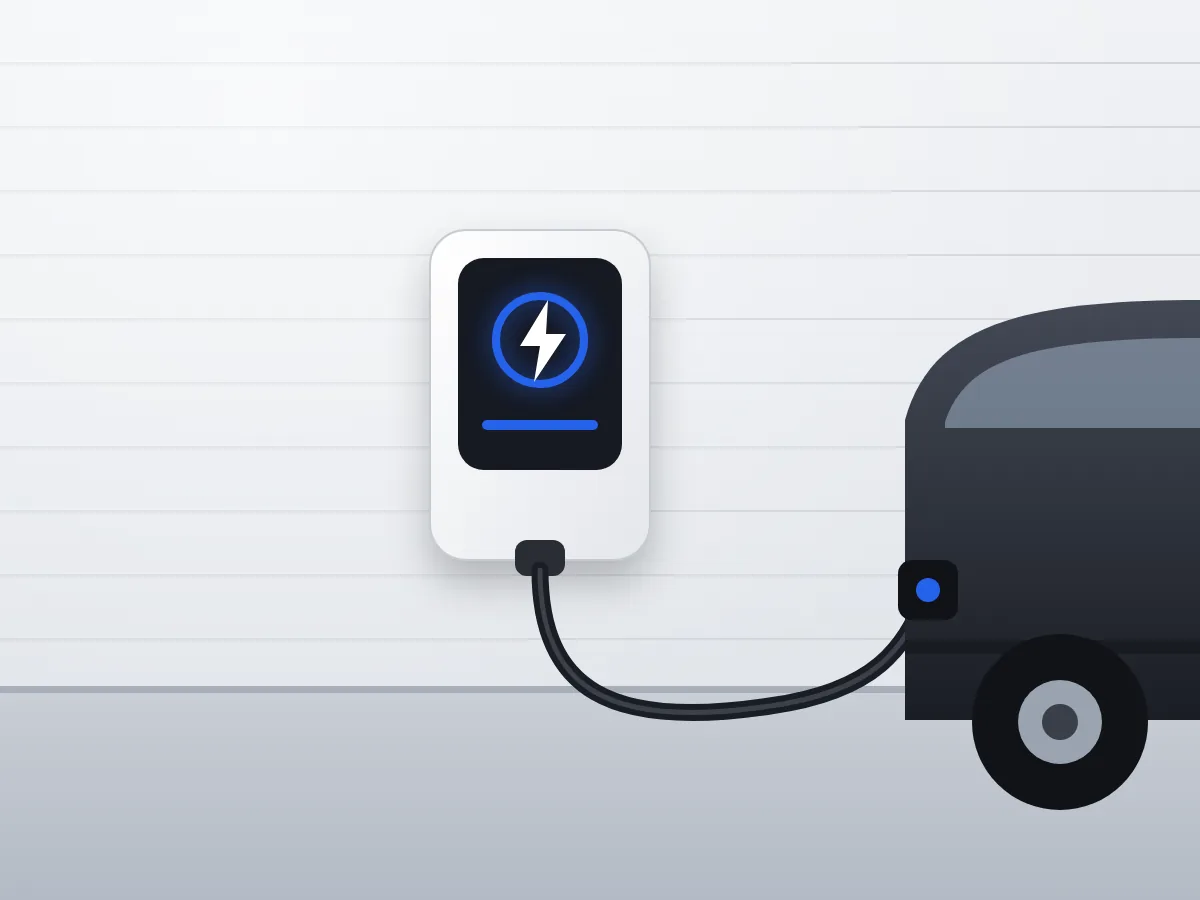 Laadpaal aan de muur van een woning, met de laadkabel aangesloten op een elektrische auto op de oprit